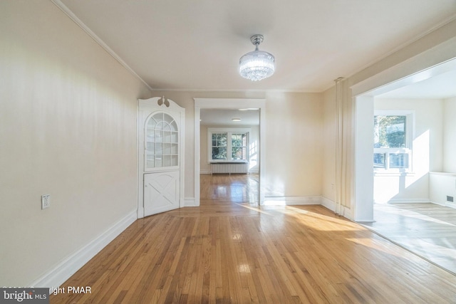 unfurnished dining area with ornamental molding, a chandelier, light wood-type flooring, and a wealth of natural light