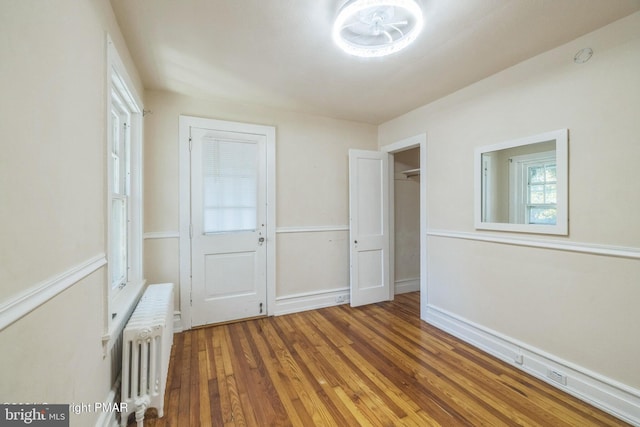 unfurnished bedroom featuring radiator heating unit and dark hardwood / wood-style floors