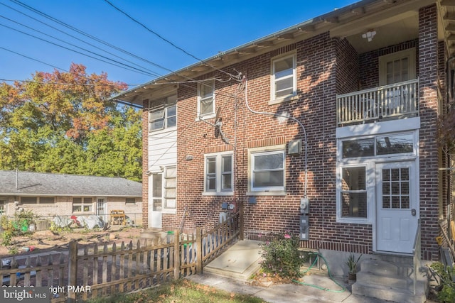 rear view of property featuring fence and brick siding