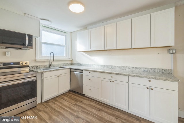 kitchen with sink, white cabinetry, stainless steel appliances, and light hardwood / wood-style floors