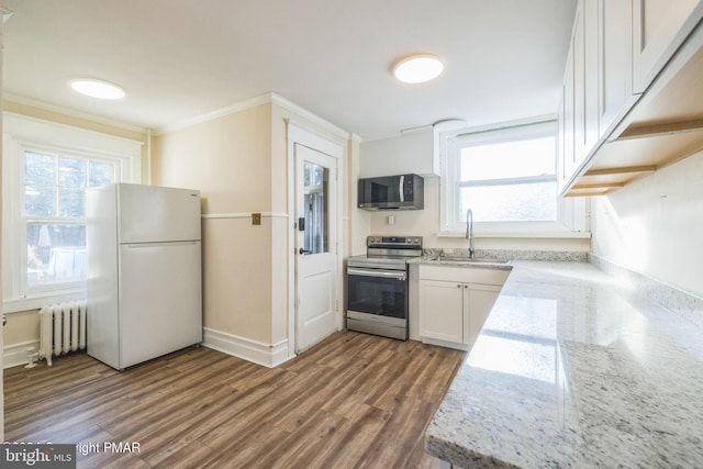 kitchen featuring appliances with stainless steel finishes, sink, hardwood / wood-style floors, radiator, and white cabinetry