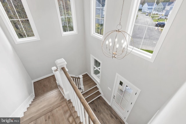 staircase featuring wood-type flooring and a notable chandelier