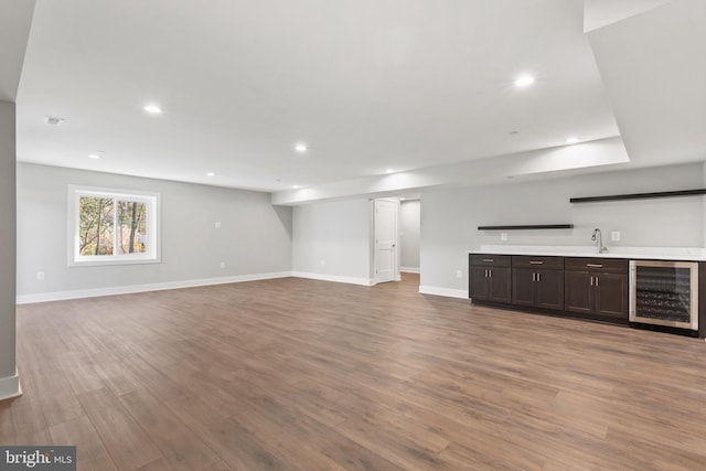 unfurnished living room with wood-type flooring, wine cooler, and wet bar