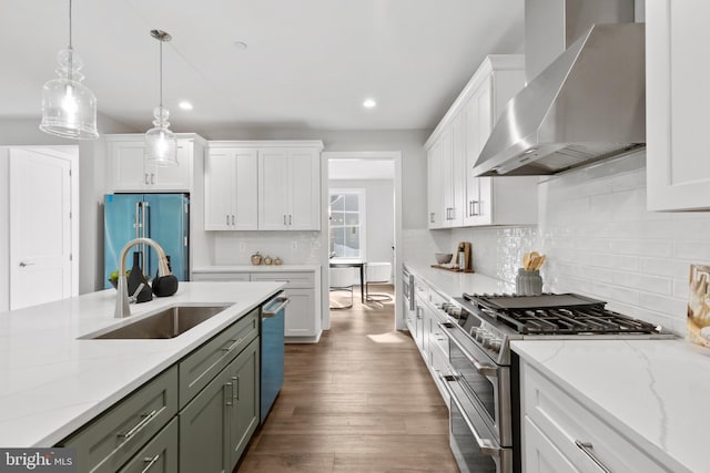 kitchen featuring sink, white cabinetry, high quality appliances, and wall chimney range hood