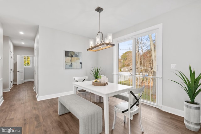 dining space with a wealth of natural light, dark hardwood / wood-style flooring, and a chandelier