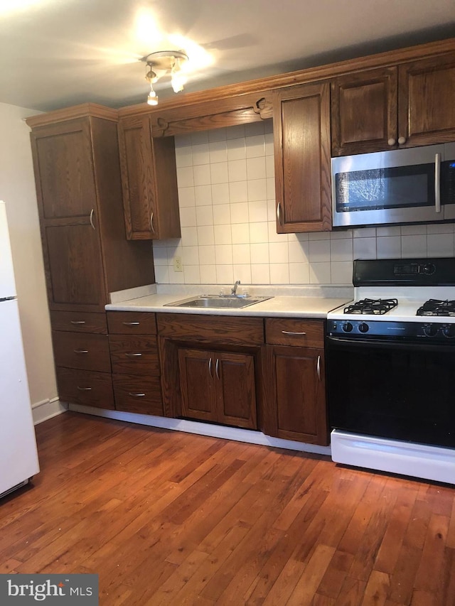 kitchen with decorative backsplash, black gas stove, white refrigerator, and dark hardwood / wood-style flooring