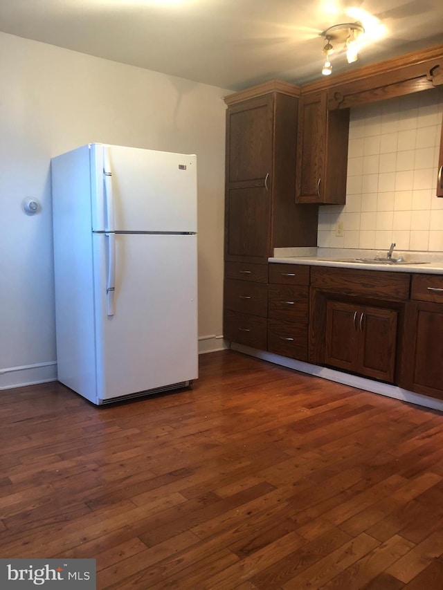 kitchen featuring tasteful backsplash, dark hardwood / wood-style floors, sink, and white refrigerator