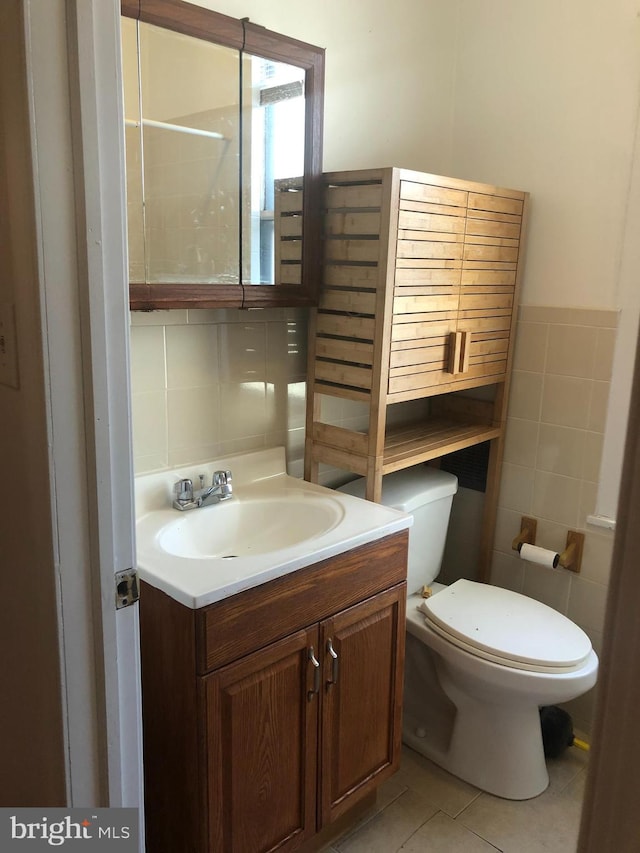 bathroom featuring toilet, vanity, tile walls, and tile patterned floors