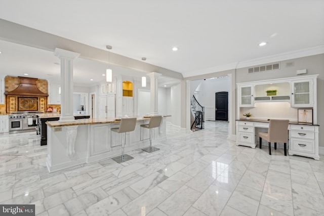 kitchen featuring ornamental molding, white cabinetry, custom range hood, hanging light fixtures, and stainless steel range