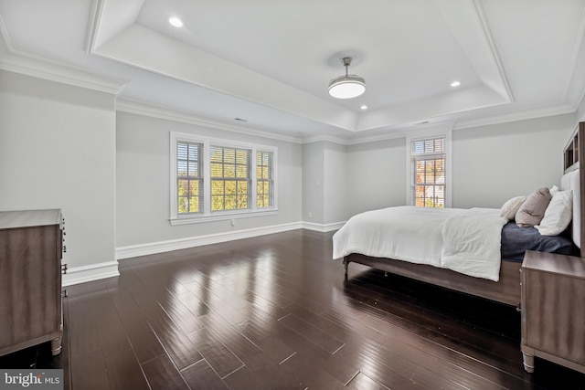 bedroom with dark wood-type flooring, a raised ceiling, and ornamental molding