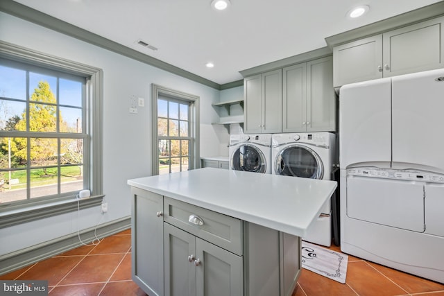 laundry area with washer and clothes dryer, dark tile patterned flooring, cabinets, and crown molding