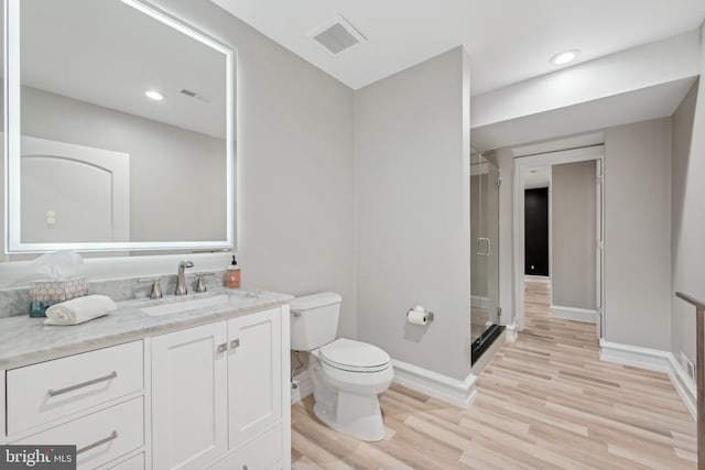 bathroom featuring toilet, an enclosed shower, vanity, and hardwood / wood-style flooring