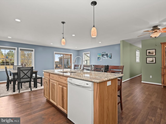 kitchen featuring a wealth of natural light, dark hardwood / wood-style flooring, white dishwasher, and an island with sink