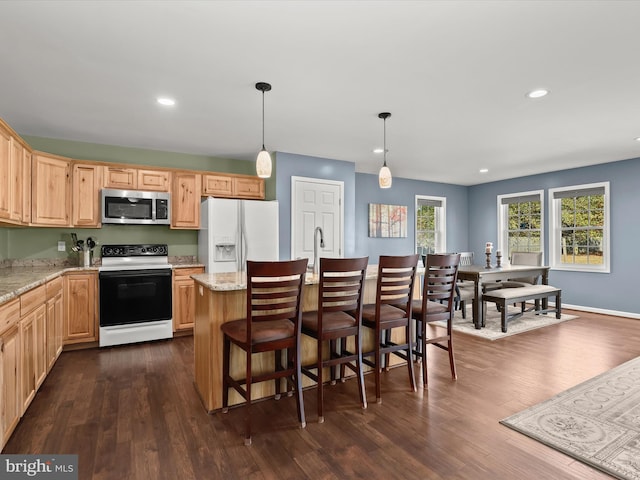 kitchen with dark wood-type flooring, white appliances, hanging light fixtures, and light stone counters