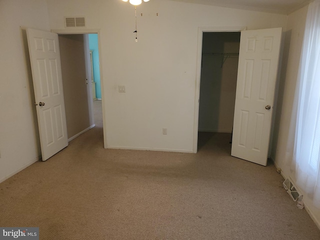 unfurnished bedroom featuring a spacious closet, vaulted ceiling, and light carpet