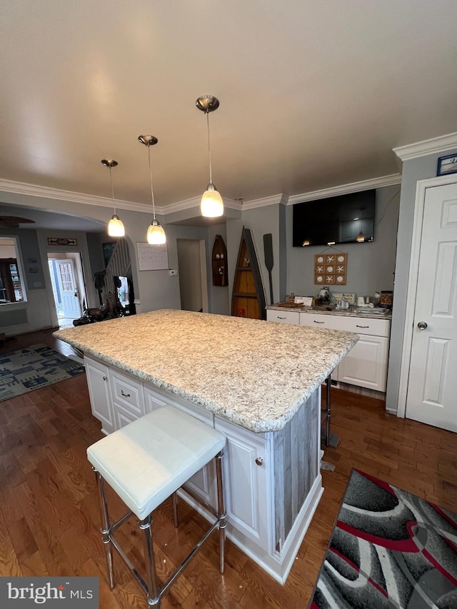 kitchen with white cabinets, a kitchen bar, and dark wood-type flooring