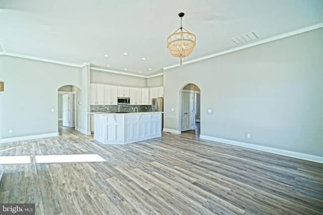 kitchen featuring pendant lighting, an inviting chandelier, white cabinets, light hardwood / wood-style flooring, and appliances with stainless steel finishes