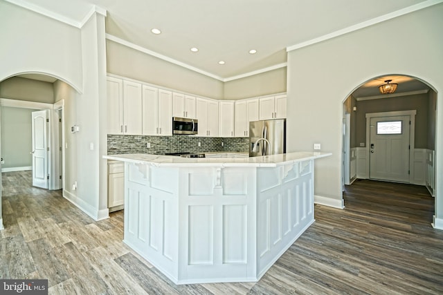 kitchen with an island with sink, white cabinets, and stainless steel appliances