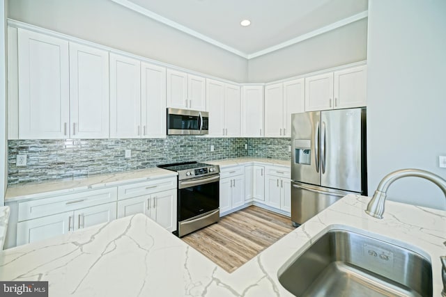 kitchen featuring sink, decorative backsplash, appliances with stainless steel finishes, light stone counters, and white cabinetry