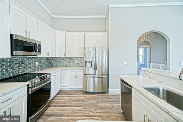 kitchen with sink, stainless steel appliances, light stone counters, light hardwood / wood-style floors, and white cabinets