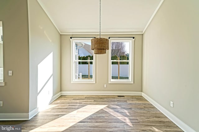 unfurnished dining area featuring wood-type flooring and crown molding