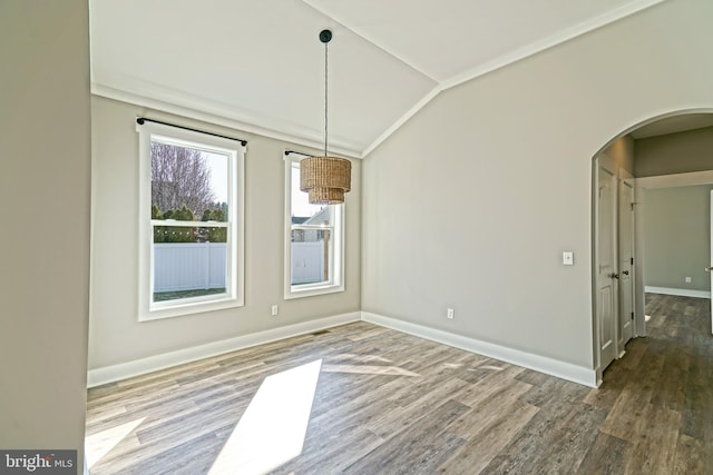 unfurnished dining area featuring hardwood / wood-style floors, vaulted ceiling, and ornamental molding