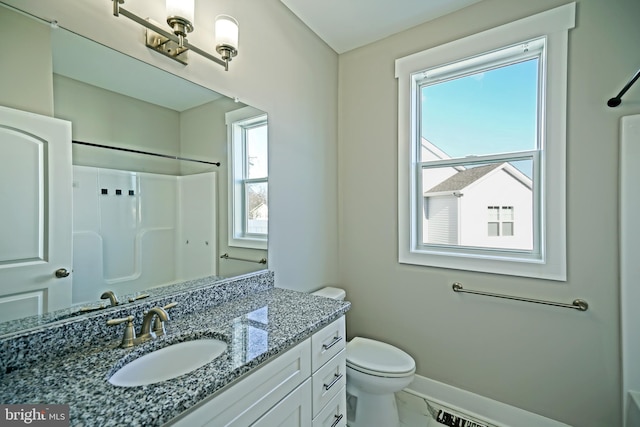 bathroom with vanity, a healthy amount of sunlight, toilet, and a shower