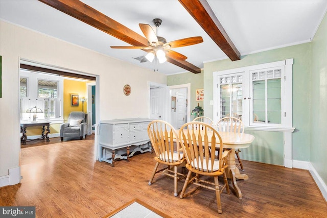 dining area featuring beamed ceiling, hardwood / wood-style flooring, and ceiling fan