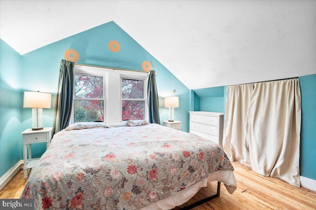 bedroom with light wood-type flooring and vaulted ceiling