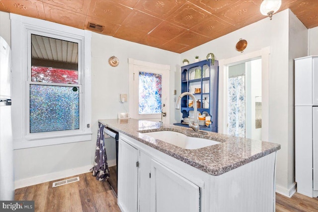 kitchen with light hardwood / wood-style floors, light stone counters, white cabinetry, and sink