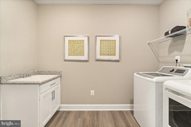 laundry room with hardwood / wood-style flooring, washer and dryer, cabinets, and sink