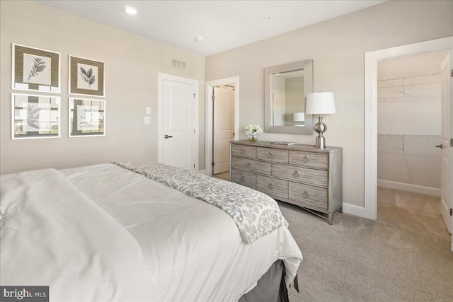 carpeted bedroom with a spacious closet and a closet