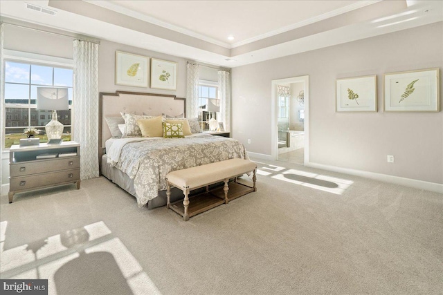 carpeted bedroom featuring a tray ceiling, ornamental molding, connected bathroom, and multiple windows