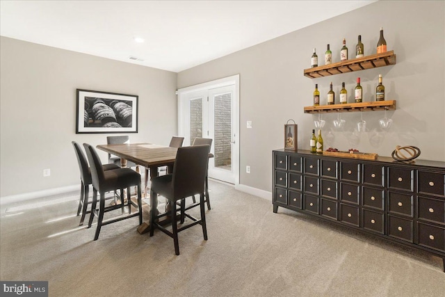 dining room with bar area and light carpet