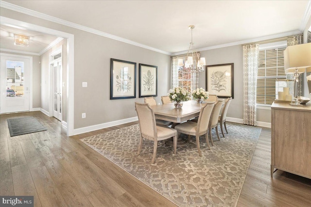 dining area featuring wood-type flooring, crown molding, and a notable chandelier