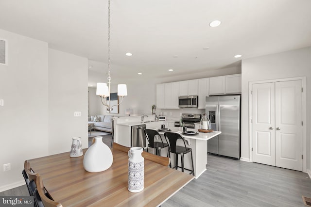 dining room featuring a chandelier, recessed lighting, light wood-type flooring, and baseboards