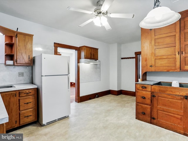 kitchen with tasteful backsplash, ceiling fan, sink, pendant lighting, and white fridge