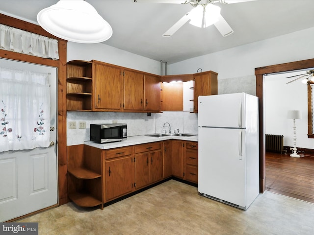 kitchen featuring tasteful backsplash, radiator, ceiling fan, sink, and white refrigerator