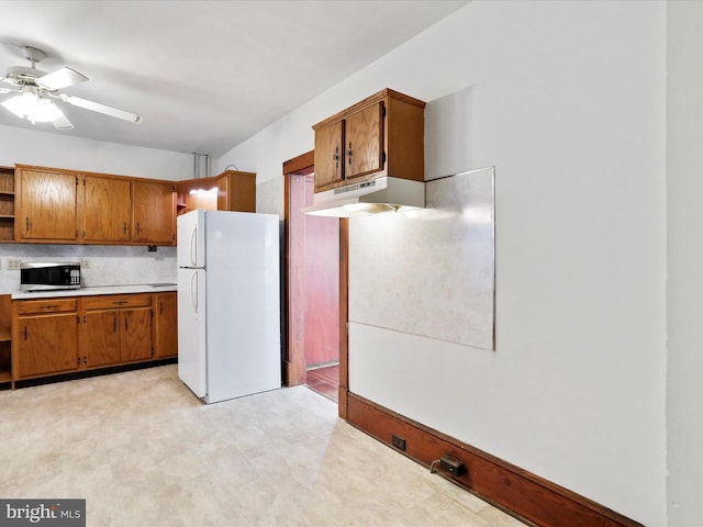 kitchen featuring ceiling fan, white refrigerator, and decorative backsplash