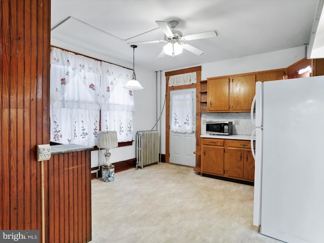 kitchen with backsplash, ceiling fan, pendant lighting, white refrigerator, and radiator heating unit