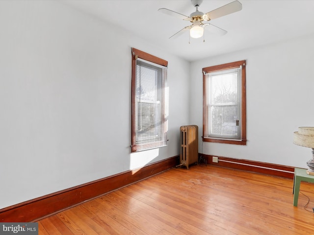 unfurnished room with radiator, ceiling fan, and light wood-type flooring