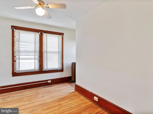 unfurnished room with radiator heating unit, light wood-type flooring, and ceiling fan