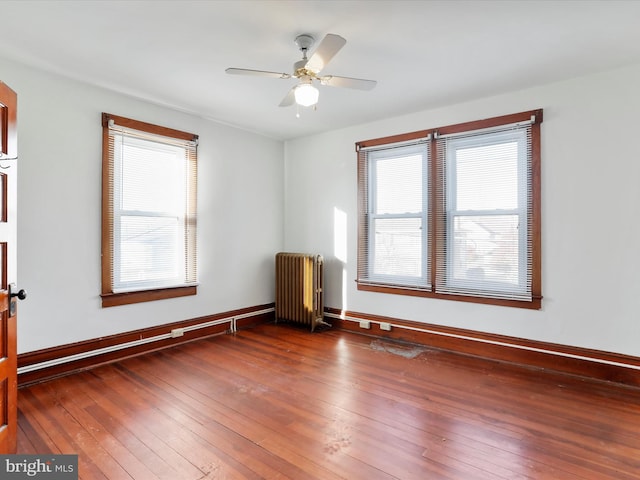 unfurnished room with dark hardwood / wood-style floors, radiator, and ceiling fan