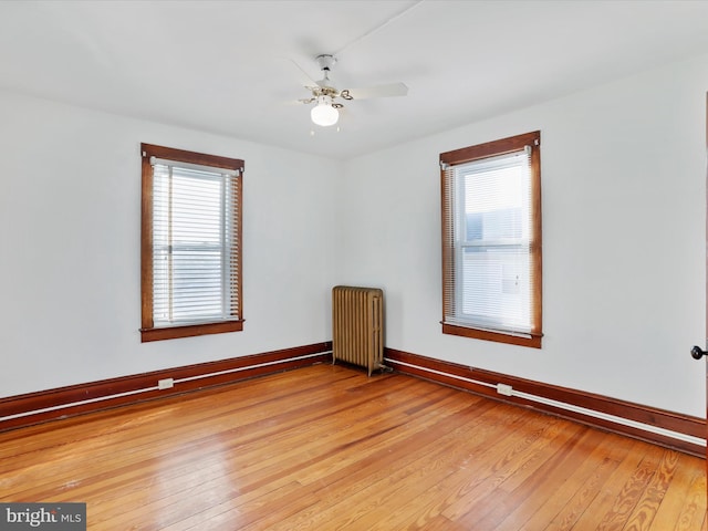 empty room featuring radiator, plenty of natural light, and light wood-type flooring