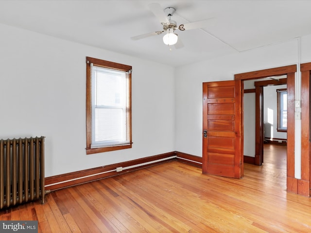 empty room with light hardwood / wood-style floors, radiator, and ceiling fan