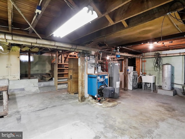 basement featuring water heater, sink, and gas water heater