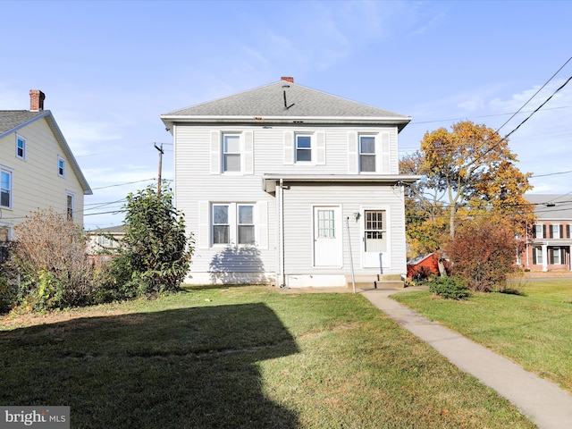 rear view of property featuring a lawn