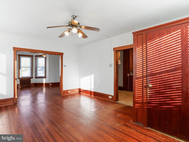 spare room with radiator, ceiling fan, and dark wood-type flooring