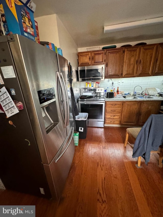 kitchen featuring sink, tasteful backsplash, appliances with stainless steel finishes, and dark hardwood / wood-style flooring