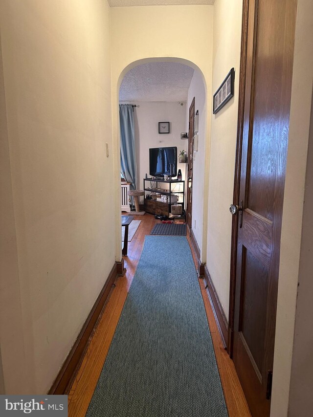 4026 9th St NE, Washington, DC 20017 - corridor featuring baseboards, arched walkways, a textured ceiling, and wood finished floors